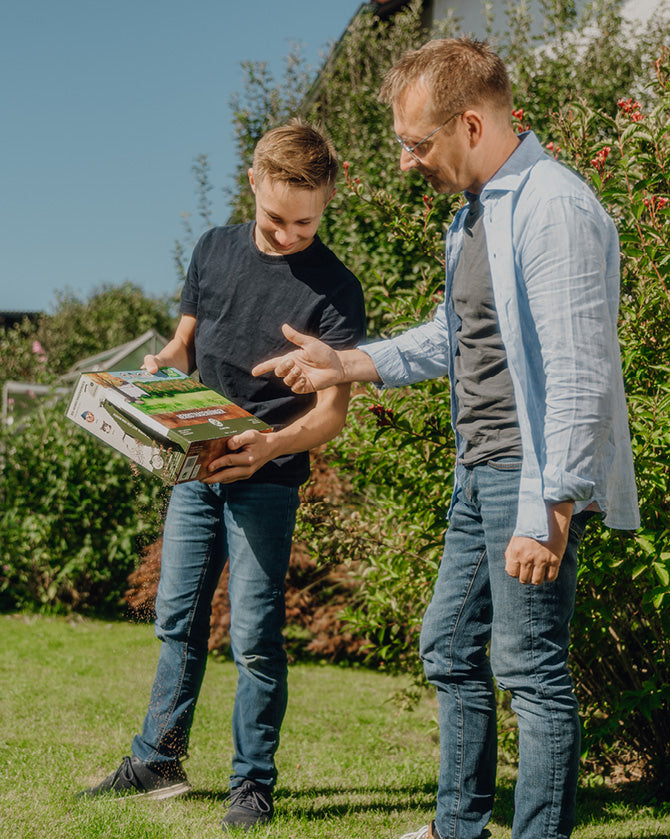 Vater und Sohn wenden Herbstrasendünger im Garten an